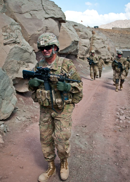 soldiers wearing camouflage walk across a dirt road