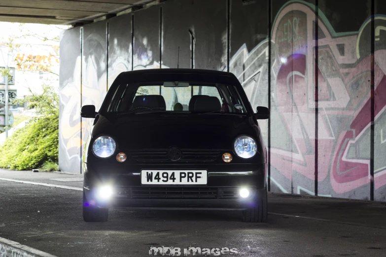 a black car with its headlights on driving through a tunnel