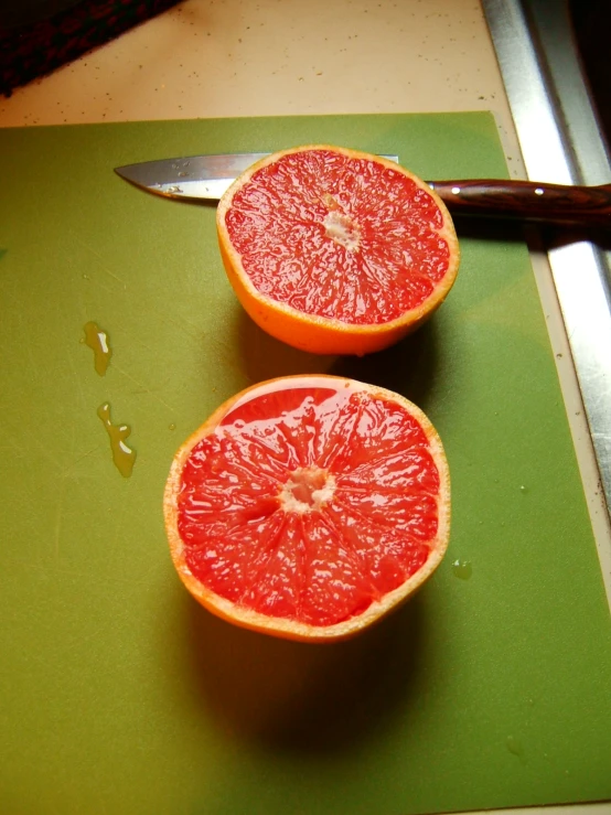 two gfruits on a  board next to a knife