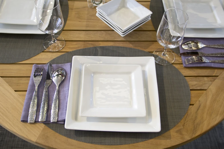 white dishes on a brown table with silver and silver napkins