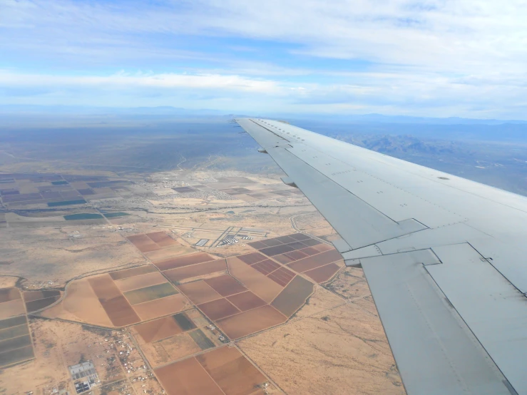 an airplane wing flying over a desert area