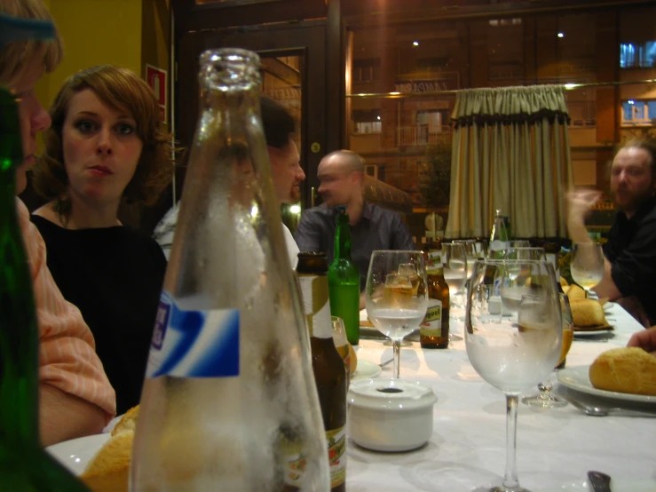 group of people sitting at a table with glasses and wine bottles