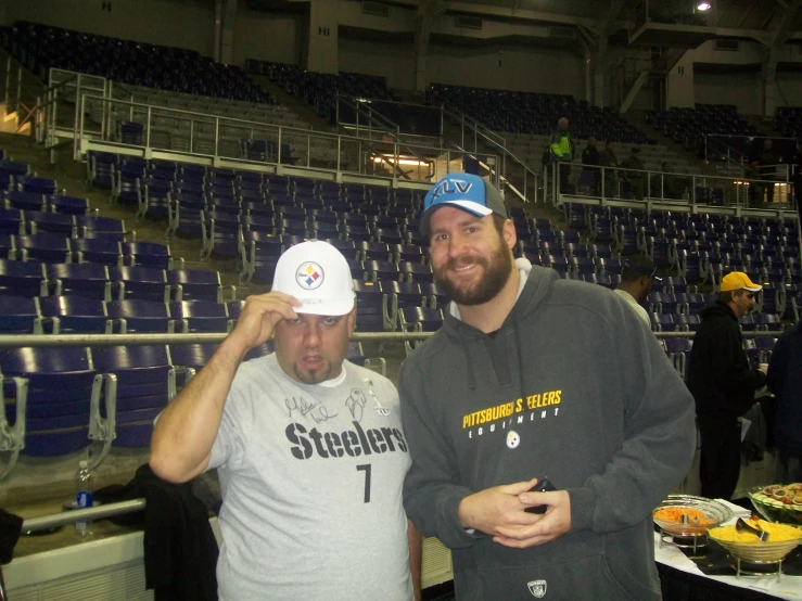 two guys at an indoor sporting event one holding his hat while the other holds his face