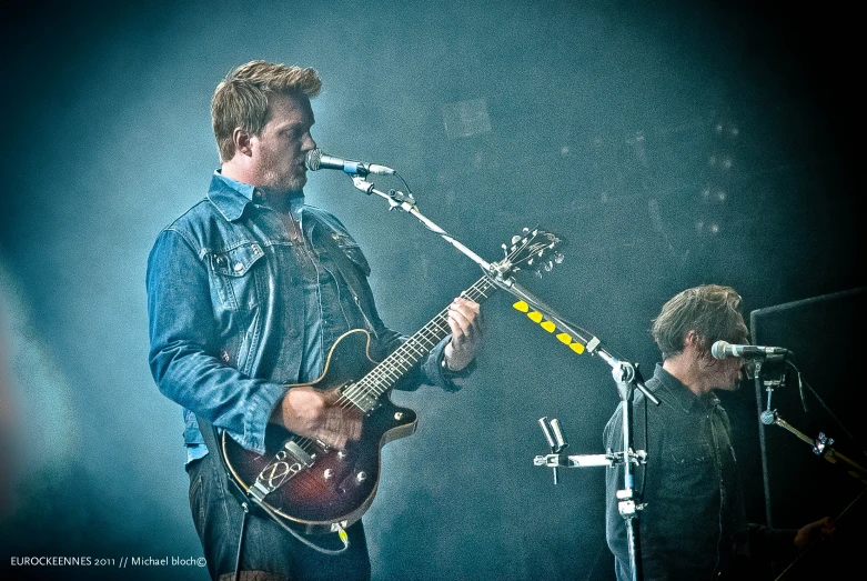 a man playing guitar on stage in front of an audience