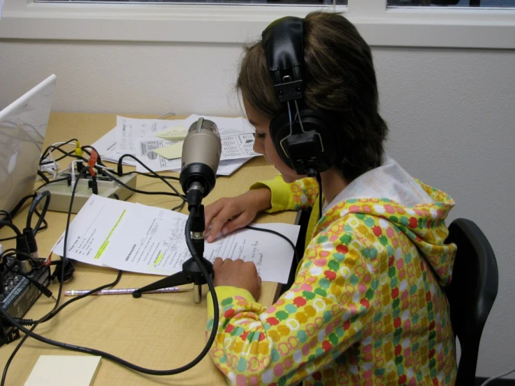 a  is sitting at her desk with headphones and a book