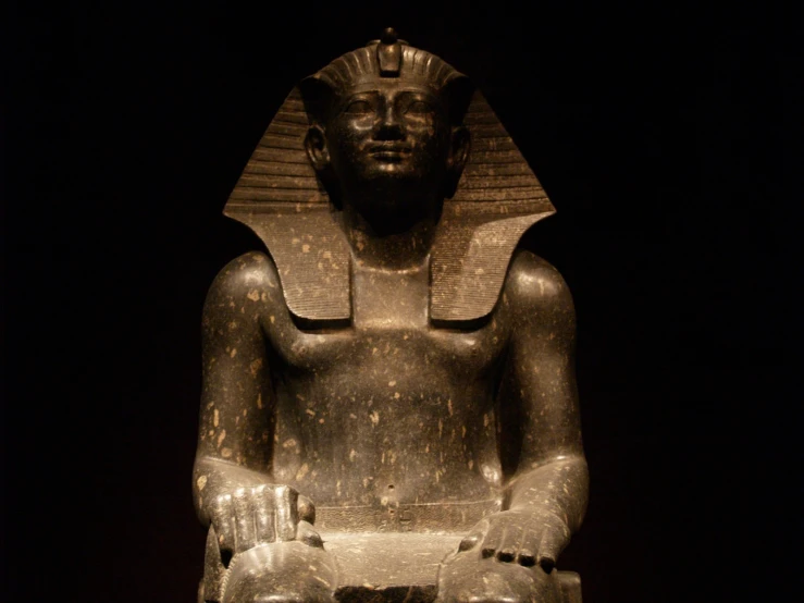 an ancient statue is shown against a dark background