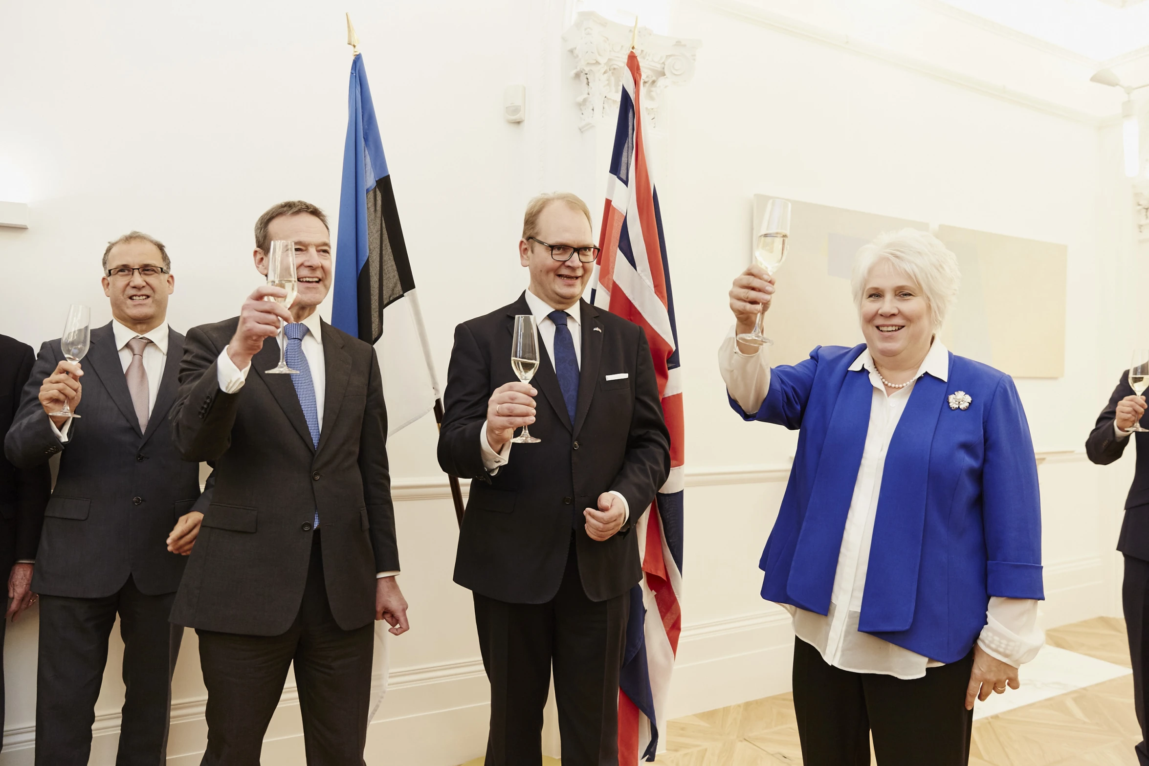 people are smiling and raising their glasses as they hold up the flags