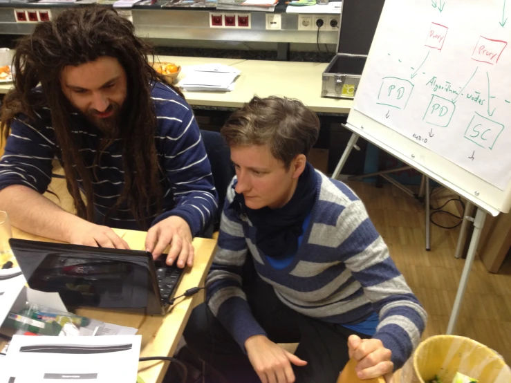 a boy in front of a computer with a boy on the other side of him