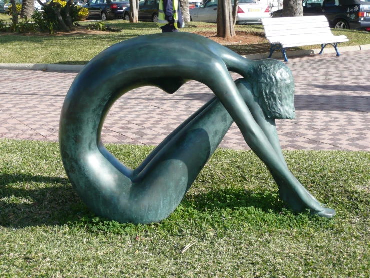 large sculpture in grassy area on sidewalk next to park