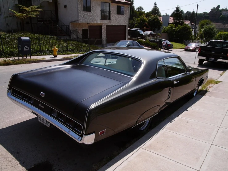 a very nice black car on a narrow residential street