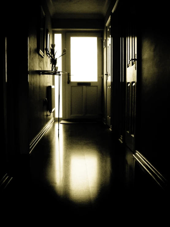 a black and white po of a hallway with a light coming through a window