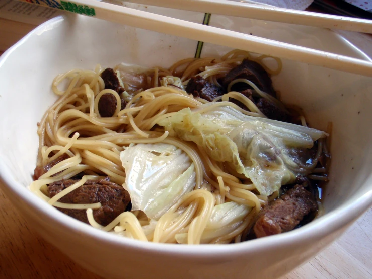 a white bowl filled with noodles and meat
