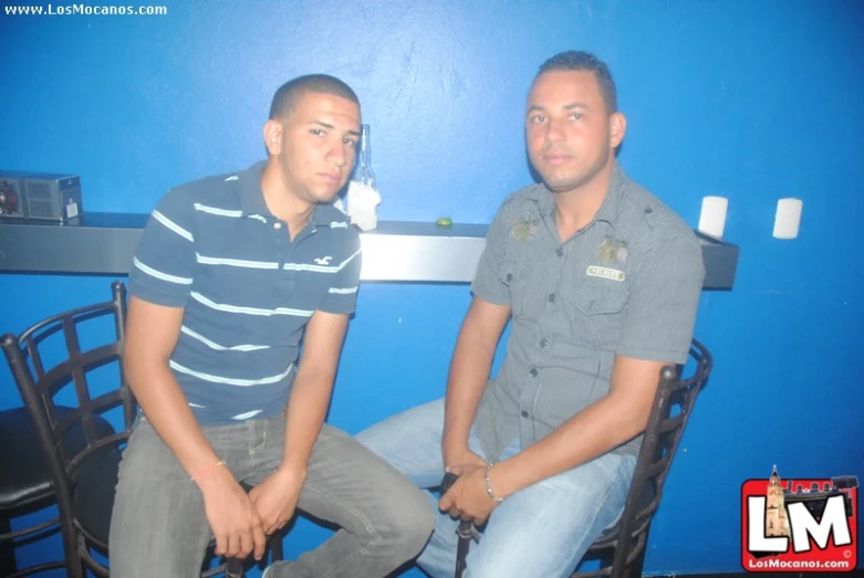 two young men sitting on a bar next to each other