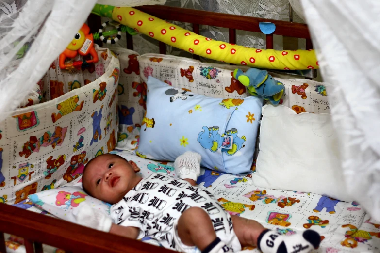 a baby sleeping in a crib surrounded by crib netting