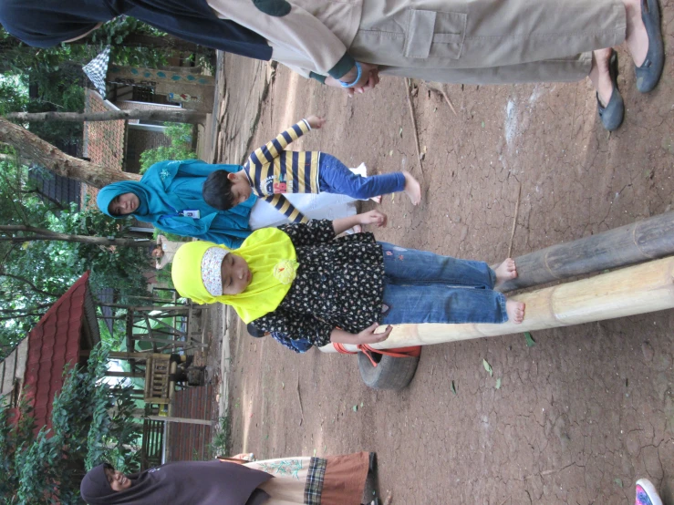 a little girl standing next to a big long wooden beam