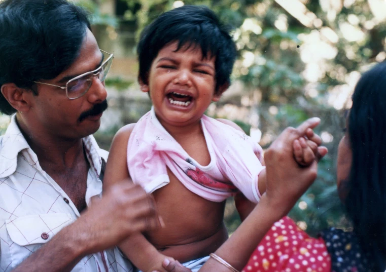 a man holding a child in his arms and a woman with an arm around them