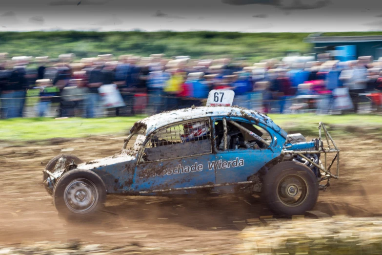 a blue dirt car speeds on an arena