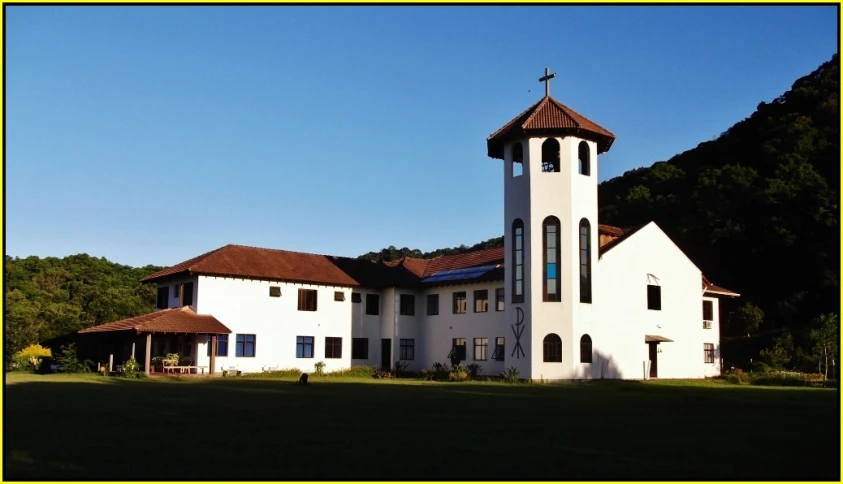 a church with trees in the background and a steeple with a cross on top