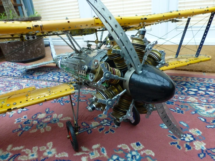 a propellor plane with gears attached to it sits on a carpet