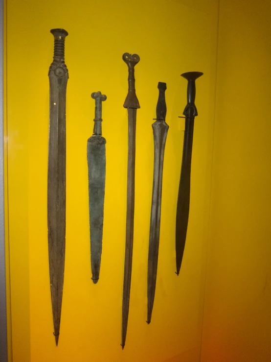 several old style knives hanging on the wall
