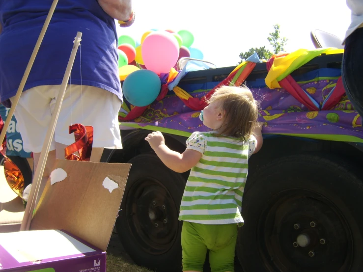 a little girl standing in front of a truck that is decorated for a parade