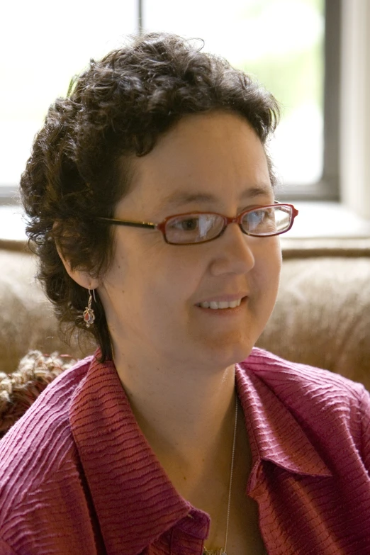 a woman in red shirt sitting in front of a window