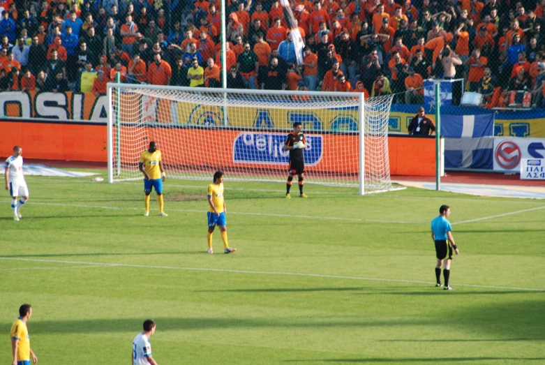 a group of people play soccer in front of an orange crowd