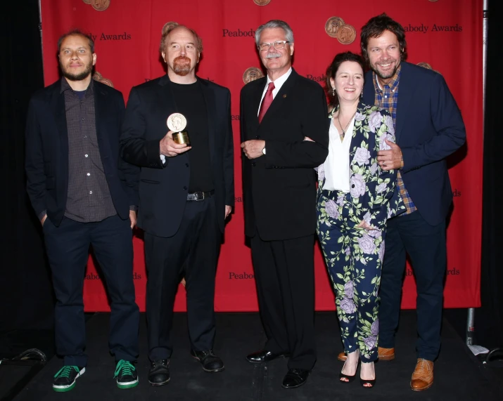 some men are posing in front of a red curtain