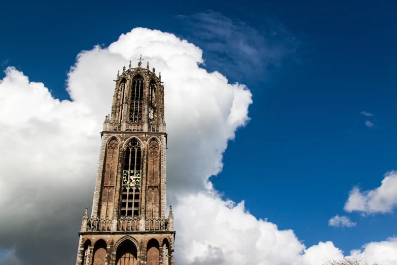 a church tower with clouds floating by in the sky