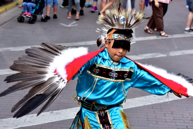 an indian boy is performing with an eagle wing