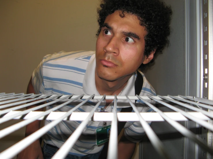 a man looking through metal bars of an object