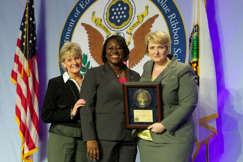 three woman posing for the camera with a plaque