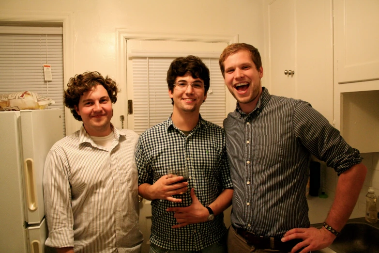 three young men are smiling and standing next to each other