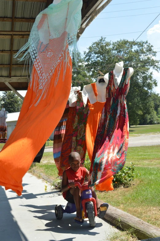 there is a child sitting in front of clothes hanging on a line