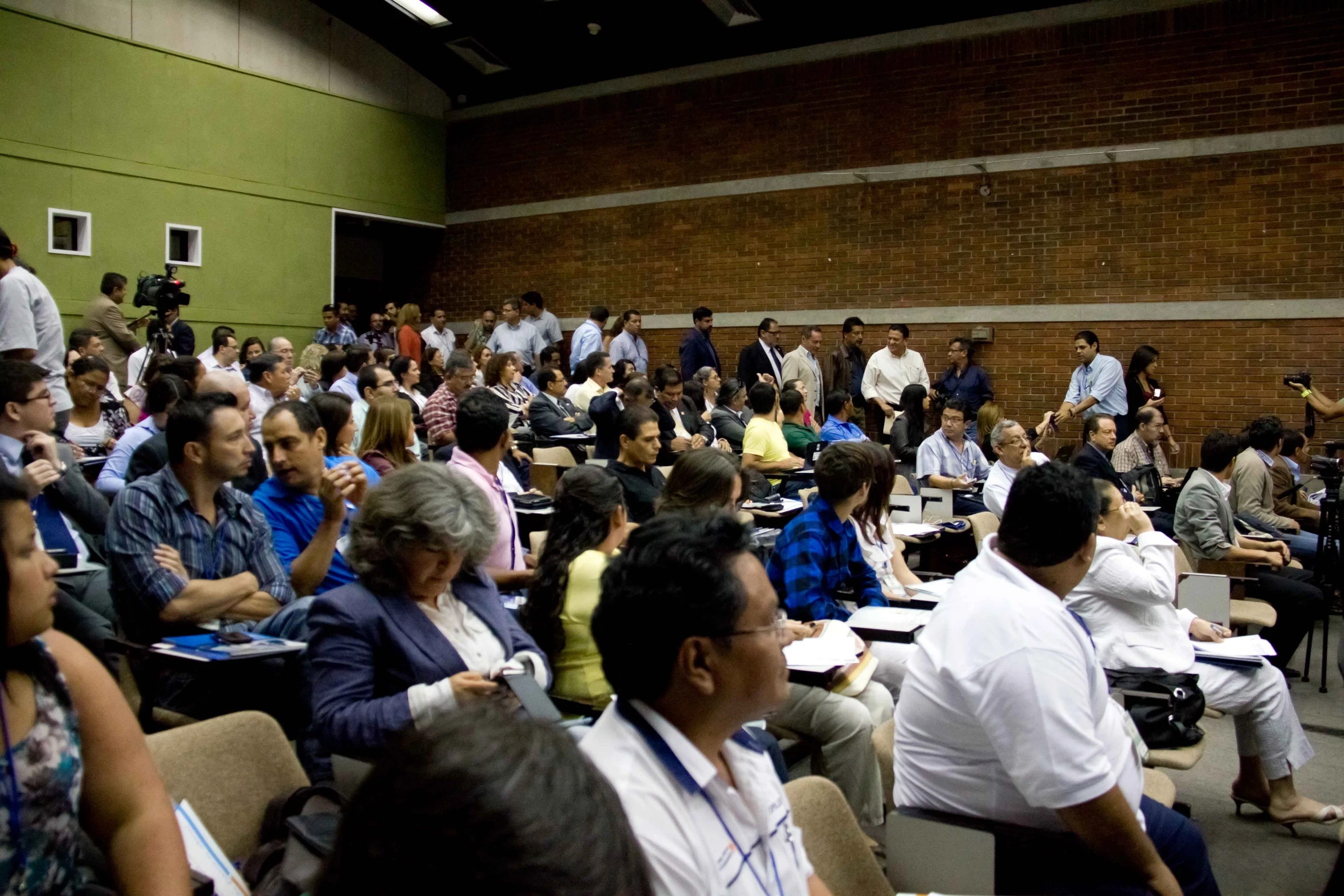 many people in chairs with papers sitting on the tables