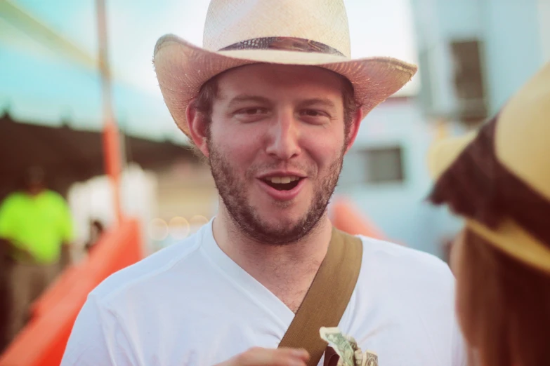 a man in a white shirt and straw hat looking at another man