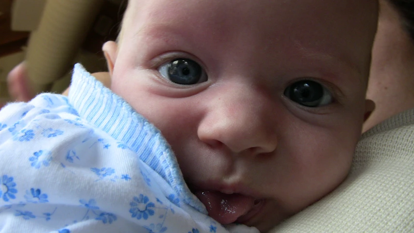 a baby chewing on the fabric of his blanket