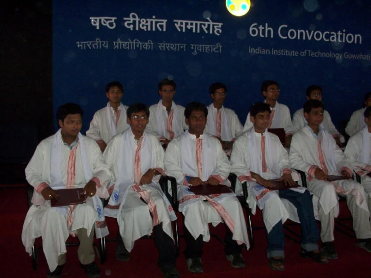 a group po of nine men in white robes on chairs