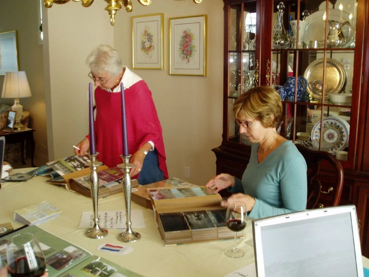 women in front of glass cases holding open books