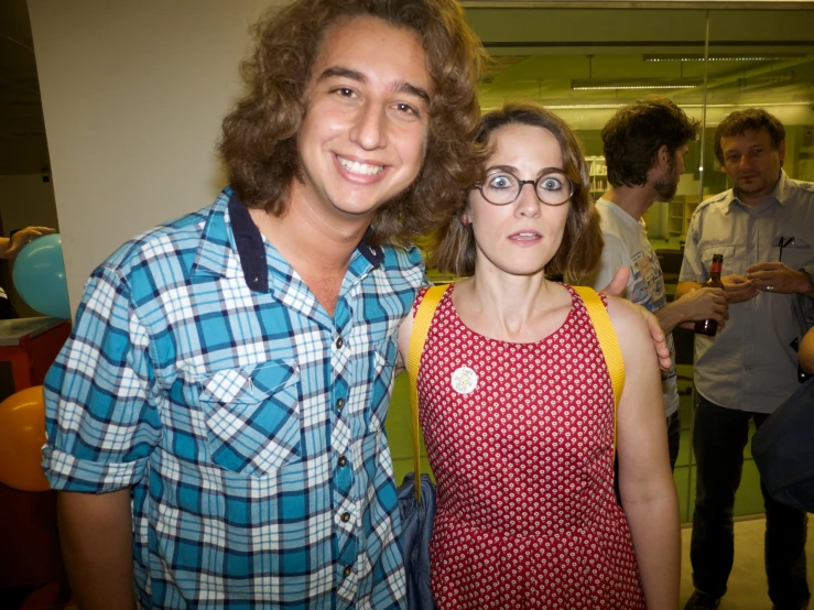 a man and woman pose for a picture in front of people