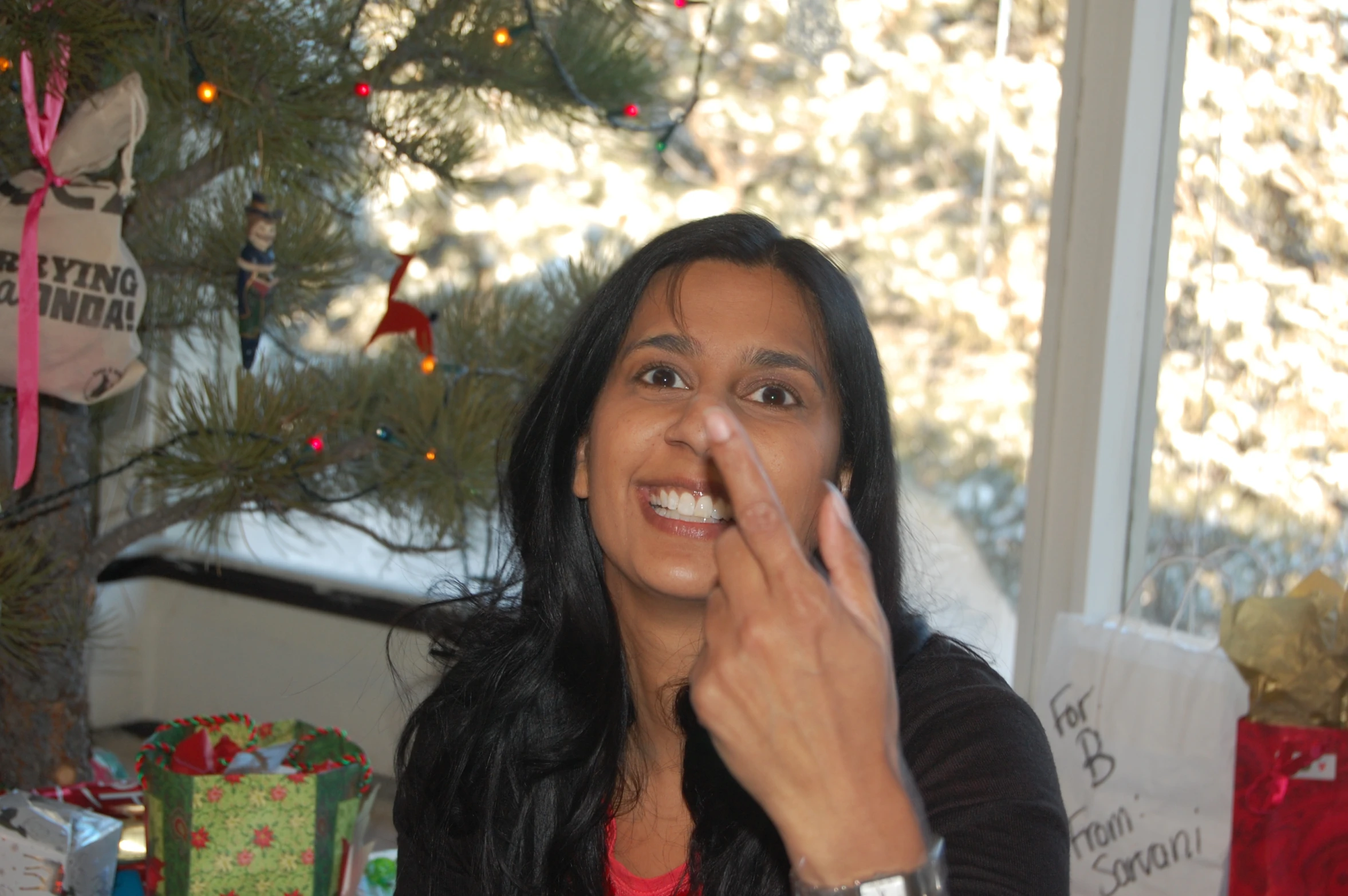 a woman standing in front of a christmas tree making a silly face