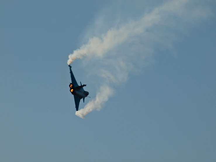 a military airplane is leaving the smoke trail