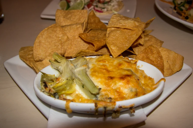 a plate with some tortilla chips, cheese and other items
