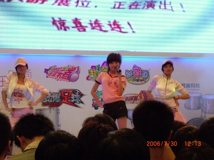 four woman standing on stage with a microphone