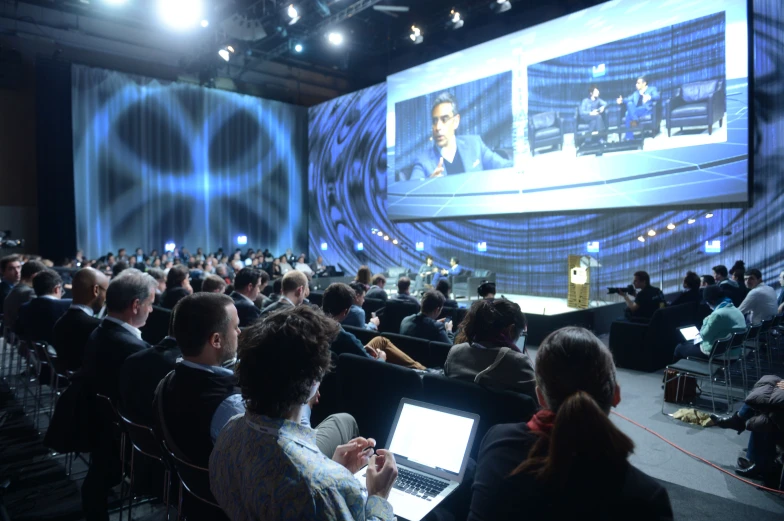 audience sitting in auditorium watching a video on a screen