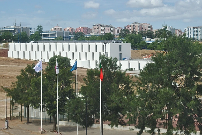 several flags flying on the wind in front of an industrial building