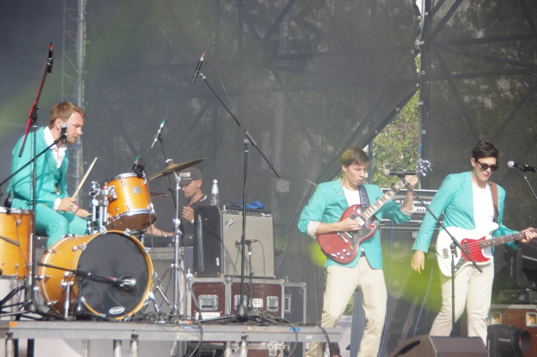 a man in a blue jacket holding a guitar on a stage