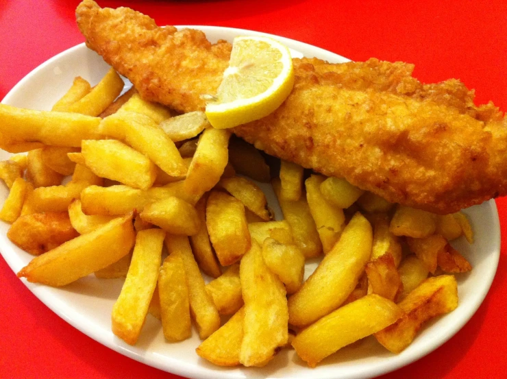 the plate is filled with fish, fries, and lemon