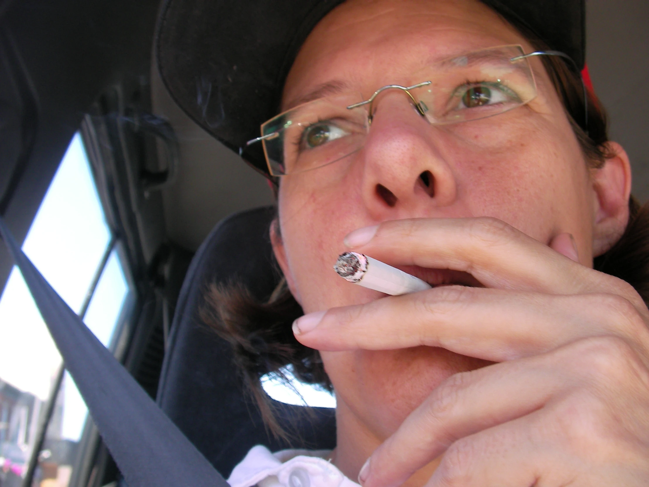 a man wearing glasses and a hat is smoking a cigarette