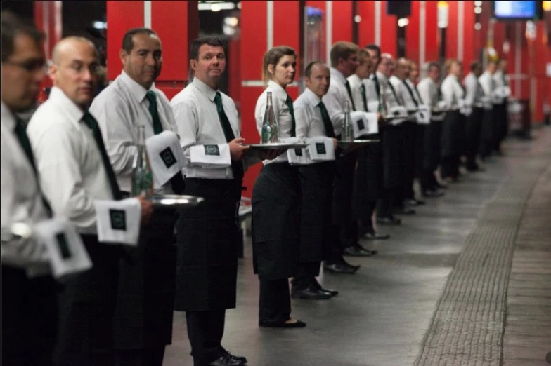 waiters in uniforms hold their plates as they wait to go out